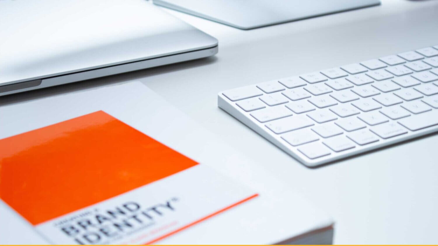 computer desk with keyboard and book that says 'Brand Identity'